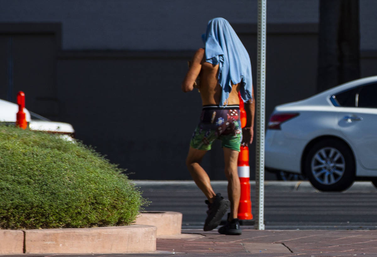 A man uses a shirt to cover his head at Sahara Avenue and Las Vegas Boulevard as temperatures c ...