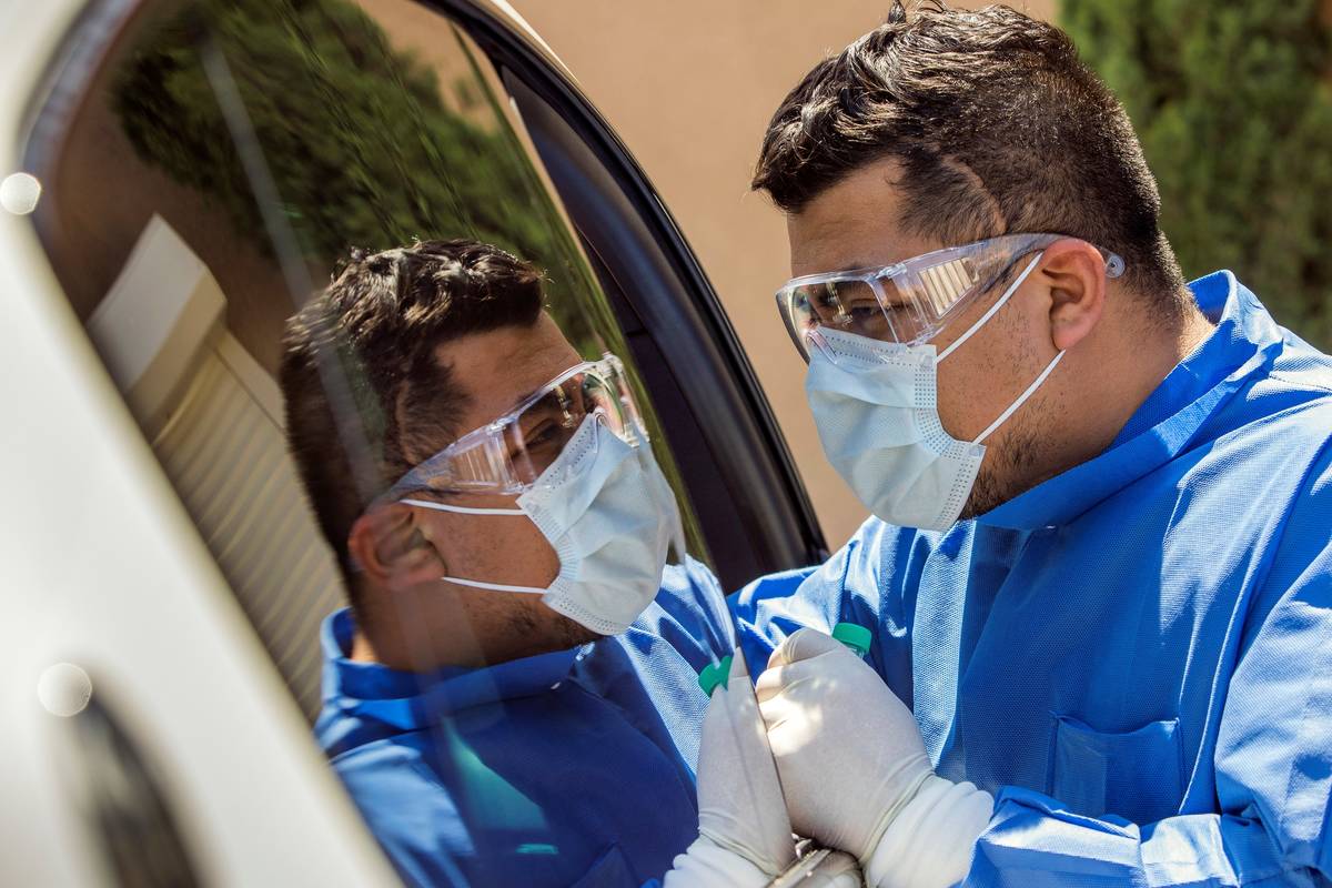 Practice Manager Jose Tirana conducts a COVID-19 test on a patient in the parking lot at Sahara ...