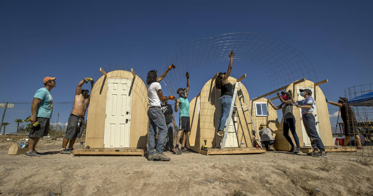 Members of Food Not Bombs and the Sidewalk Project secure a wire mesh layer as they work to con ...