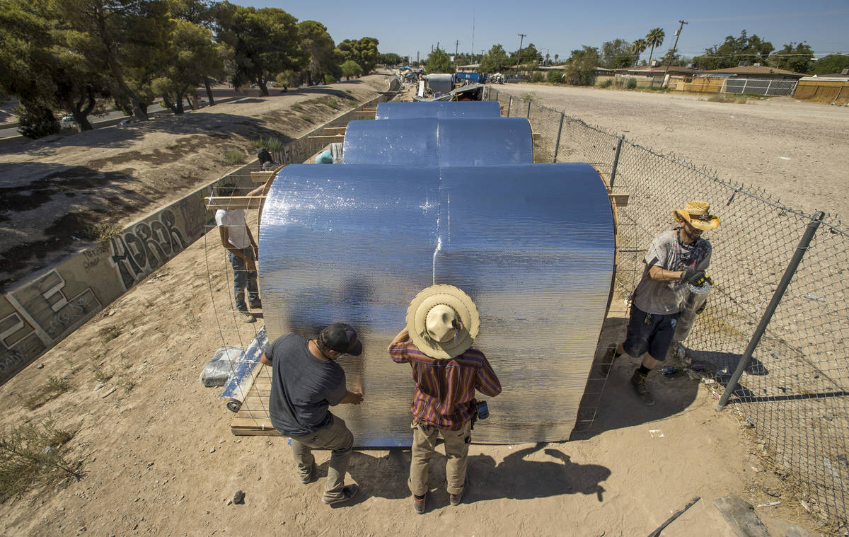 (From left) Tyler Teresi, Nick Cantu and Richard Ward secure an insulation layer with other mem ...