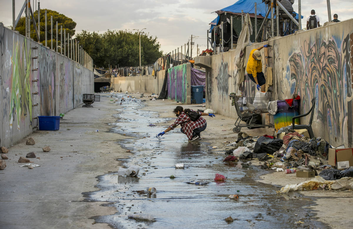 Isabel Coultas, left, and Elijah Mercer pick up trash in a water mitigation channel with member ...