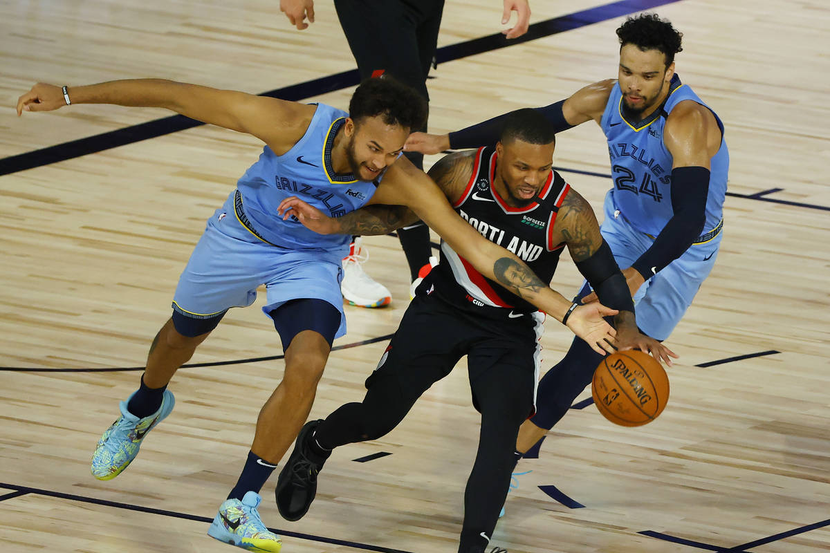 Portland Trail Blazers' Damian Lillard is pressured by Memphis Grizzlies' Kyle Anderson, left, ...