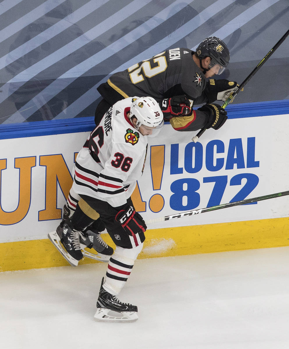 Vegas Golden Knights' Nick Holden (22) is checked by Chicago Blackhawks' Matthew Highmore (36) ...