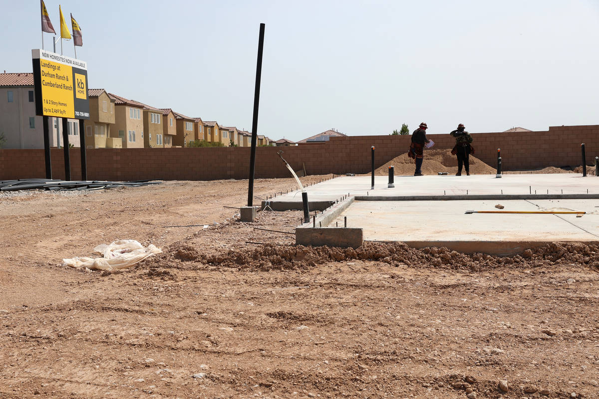 Workers stand on the slab foundation of a future home near S Fort Apache Road and W Gomer Road ...