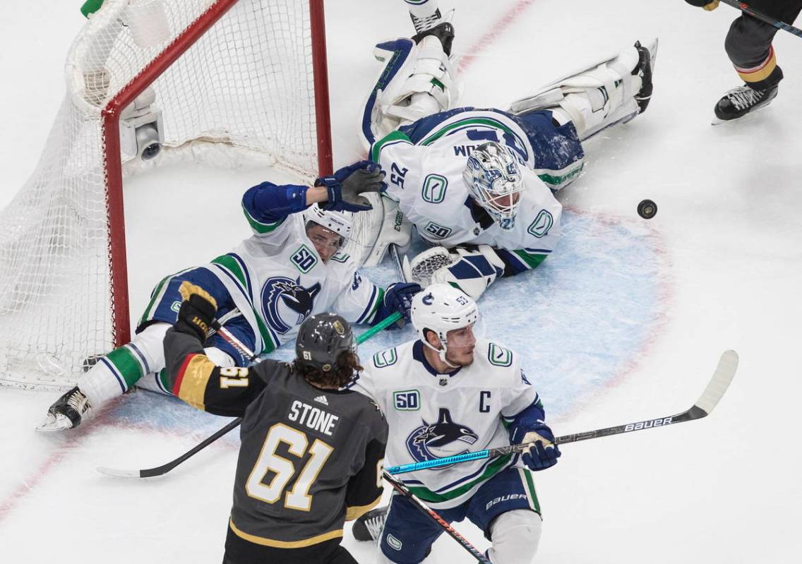 Vegas Golden Knights' Mark Stone (61) and Vancouver Canucks' Bo Horvat (53) battle in front as ...