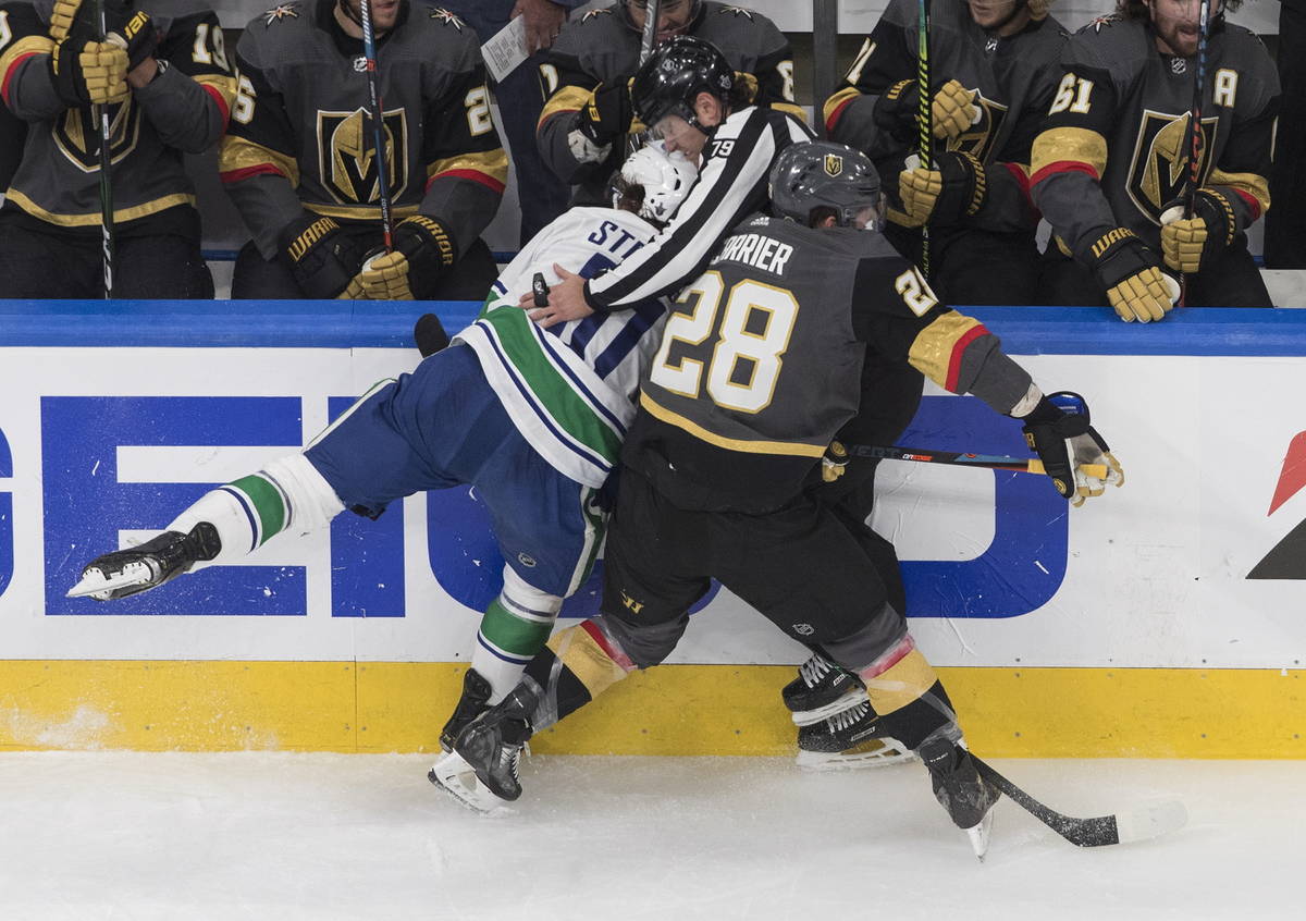 Vegas Golden Knights' William Carrier (28) and Vancouver Canucks' Troy Stecher (51) run into an ...