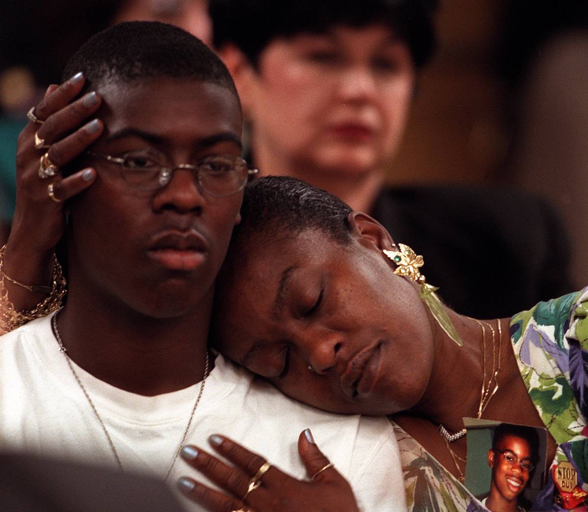 Brigitte Smith embraces her son T.J., 15, with a picture of her dead son, Anthony, 14, strapped ...