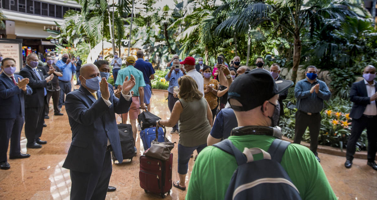 Employees applaud while greeting guests entering the front doors as the Mirage reopens followin ...