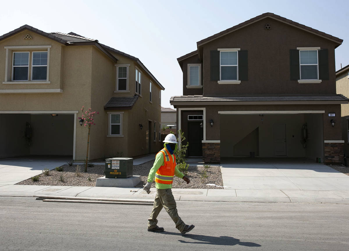 A construction worker walks past single family homes at a single-family-housing rental project ...