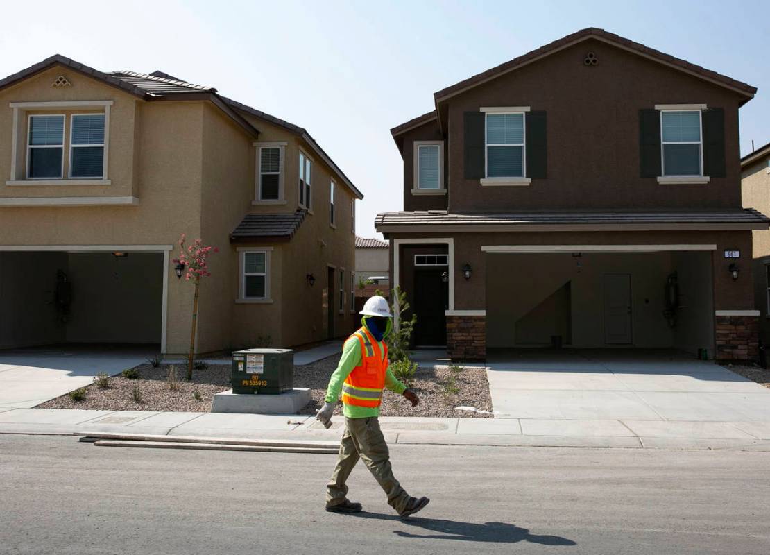 A construction worker walks past single family homes at a single-family-housing rental project ...