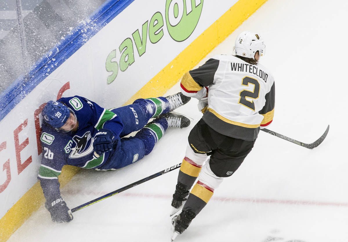 Vegas Golden Knights' Zach Whitecloud (2) checks Vancouver Canucks' Antoine Roussel (26) during ...