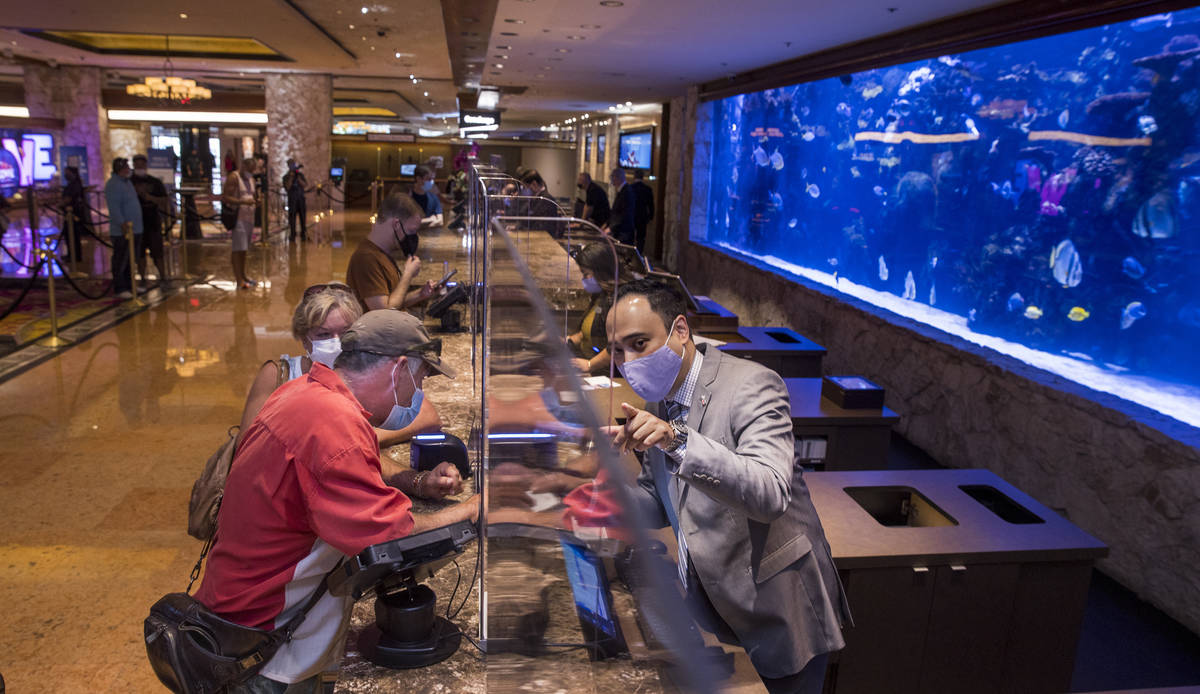 Front desk clerk Charlie Tran, right, helps to check in guests Mike and Debra Kennedy in from O ...