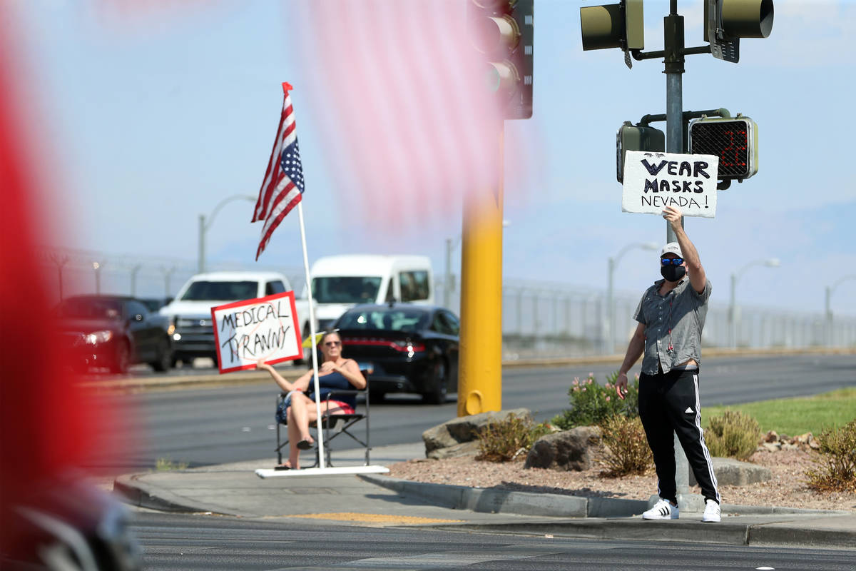 Counter protester Sascha Alexander displays his sign during a No Mask Nevada PAC rally at Sunse ...