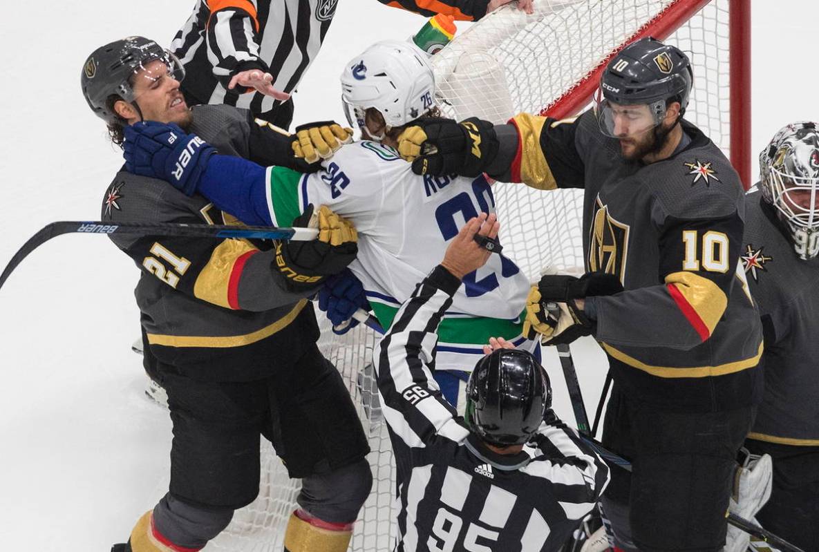 Vancouver Canucks' Antoine Roussel (26) and Vegas Golden Knights' Nick Cousins (21) and Nicolas ...