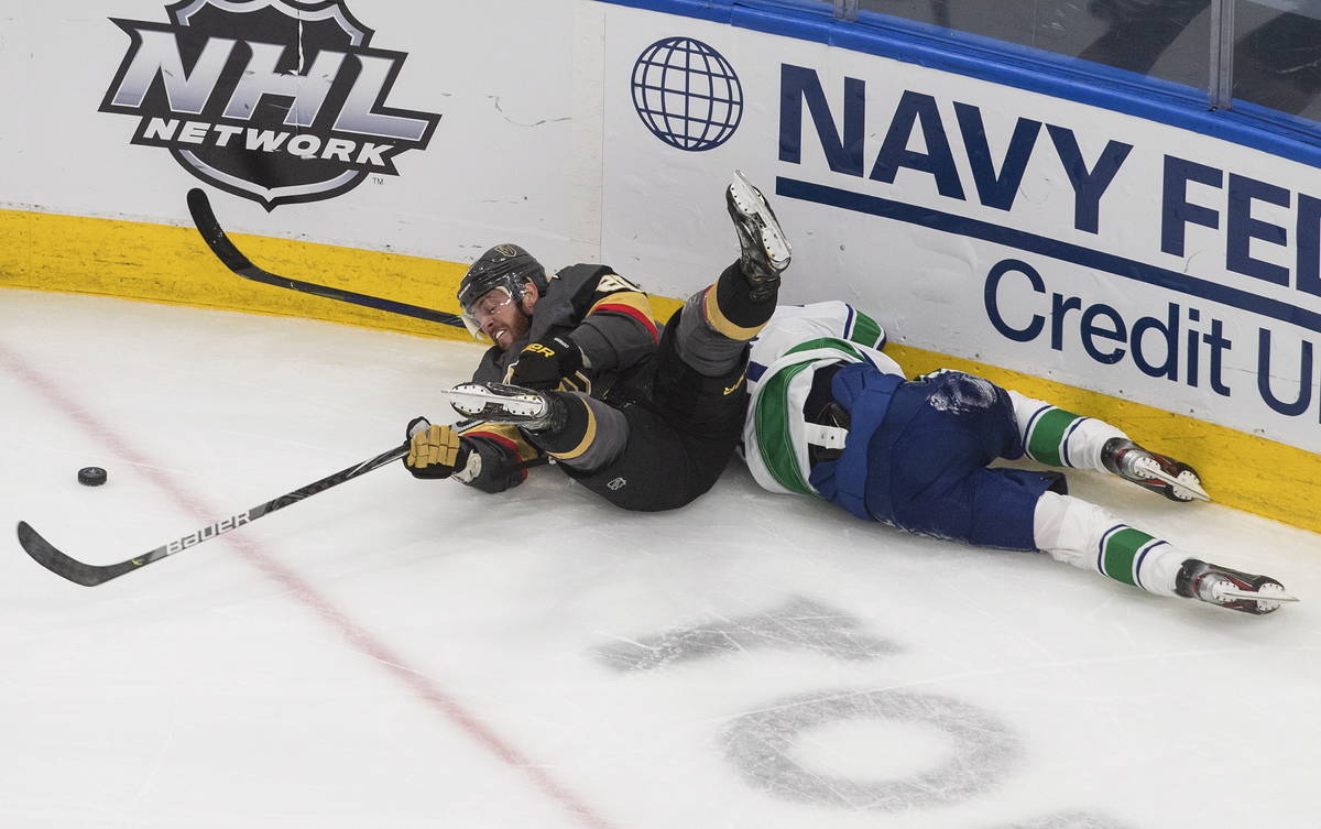Vancouver Canucks' Troy Stecher, right, battles for the puck with Vegas Golden Knights' Nick Co ...