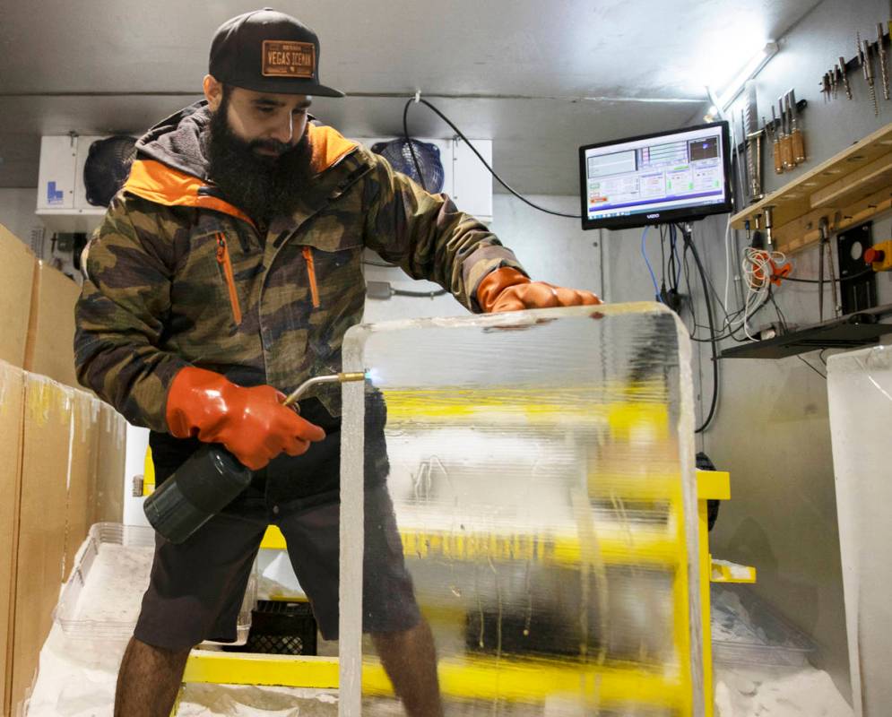 Marco Villarreal, known as "Vegas Ice Man," uses a torch to prep a fresh ice block on ...