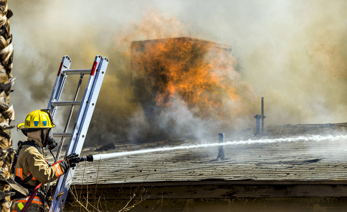 Fire burns through the roof as Las Vegas firefighters battle a house fire on 5400 block of West ...