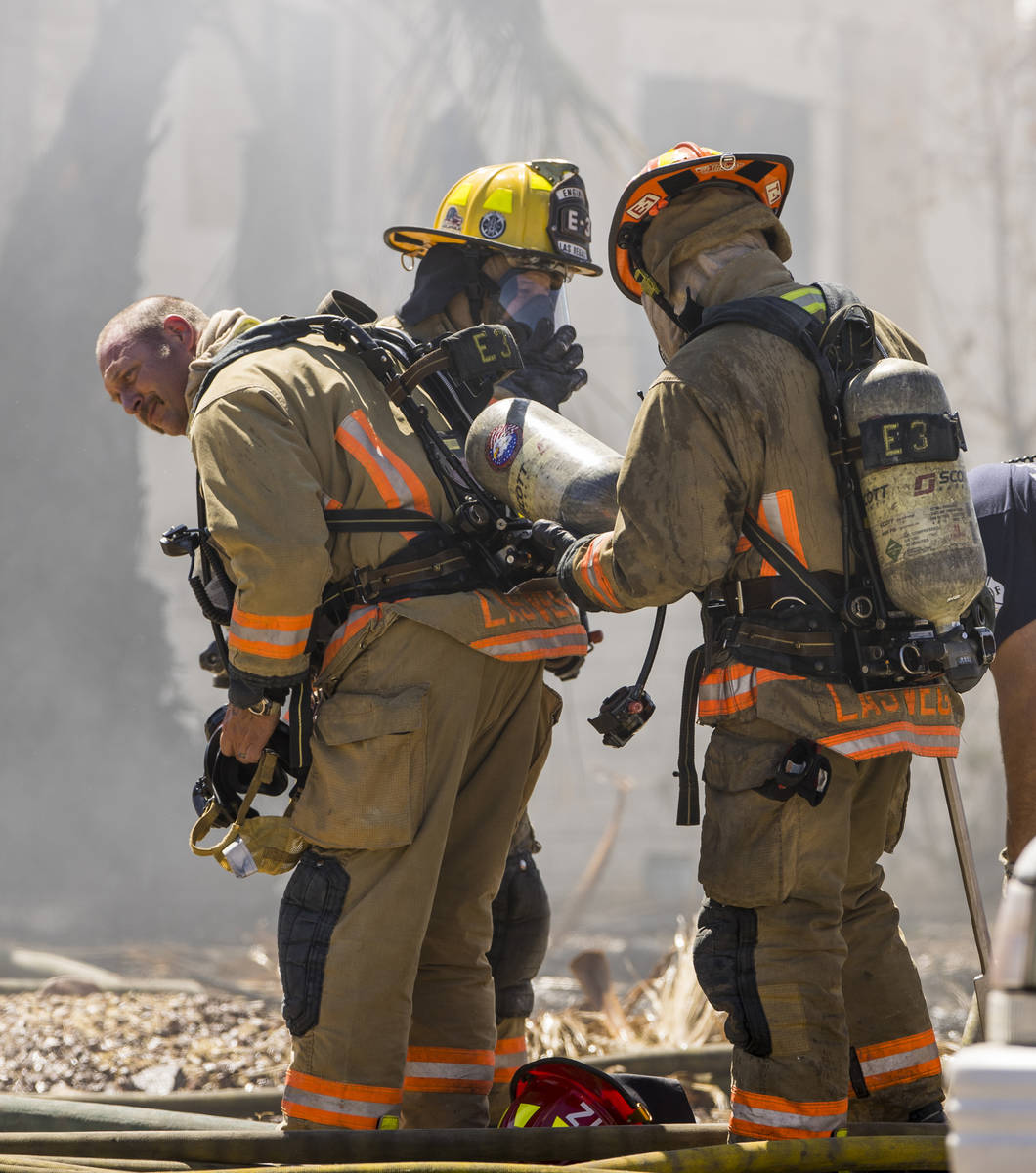 Las Vegas firefighters switch out used oxygen tanks as they battle a house fire on 5400 block o ...