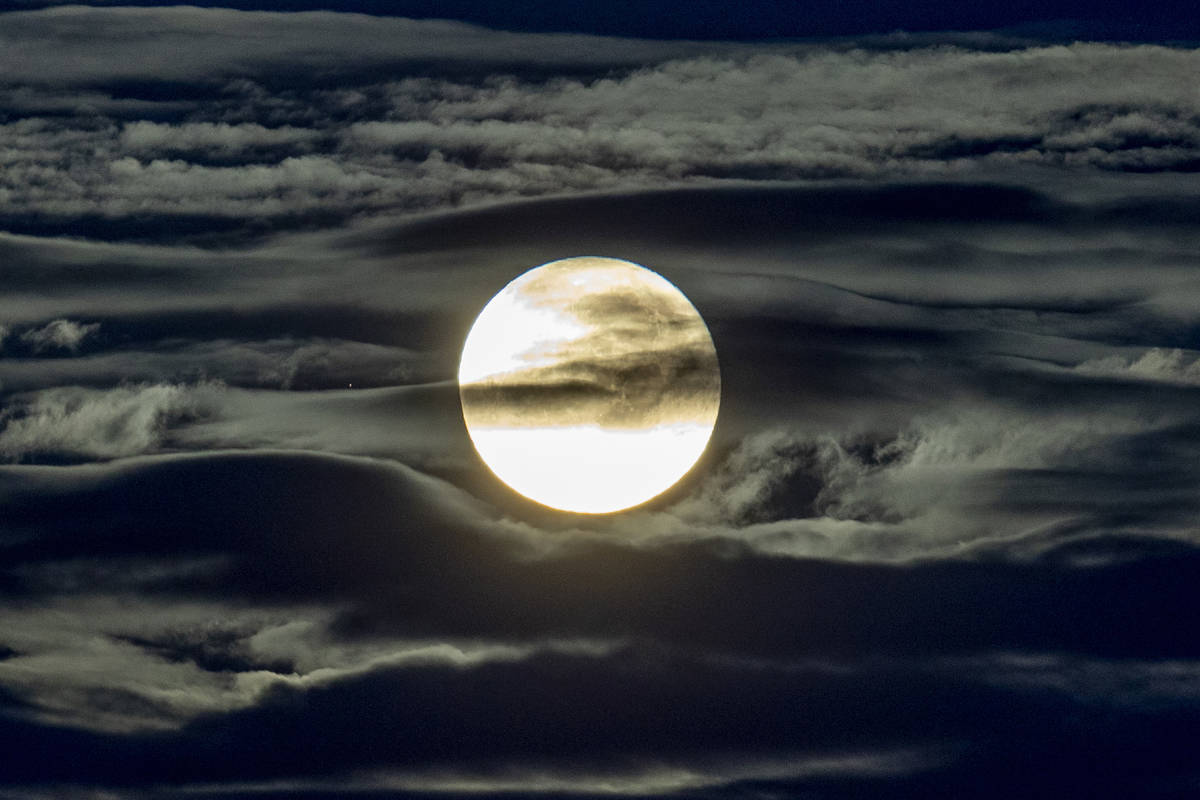 The full moon shines surrounded by clouds in the outskirts of Frankfurt, Germany, early Wednesd ...