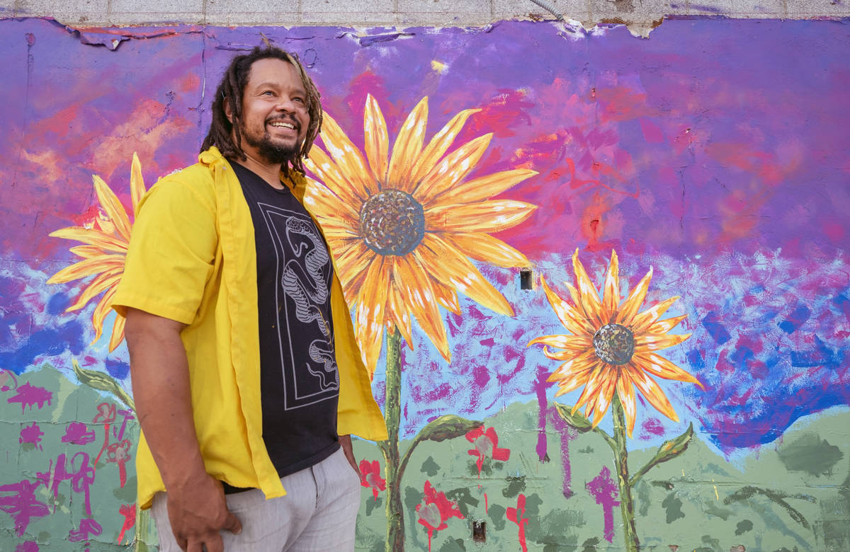 Multidisciplinary artist and community activist Brent Holmes is photographed by a mural he is w ...