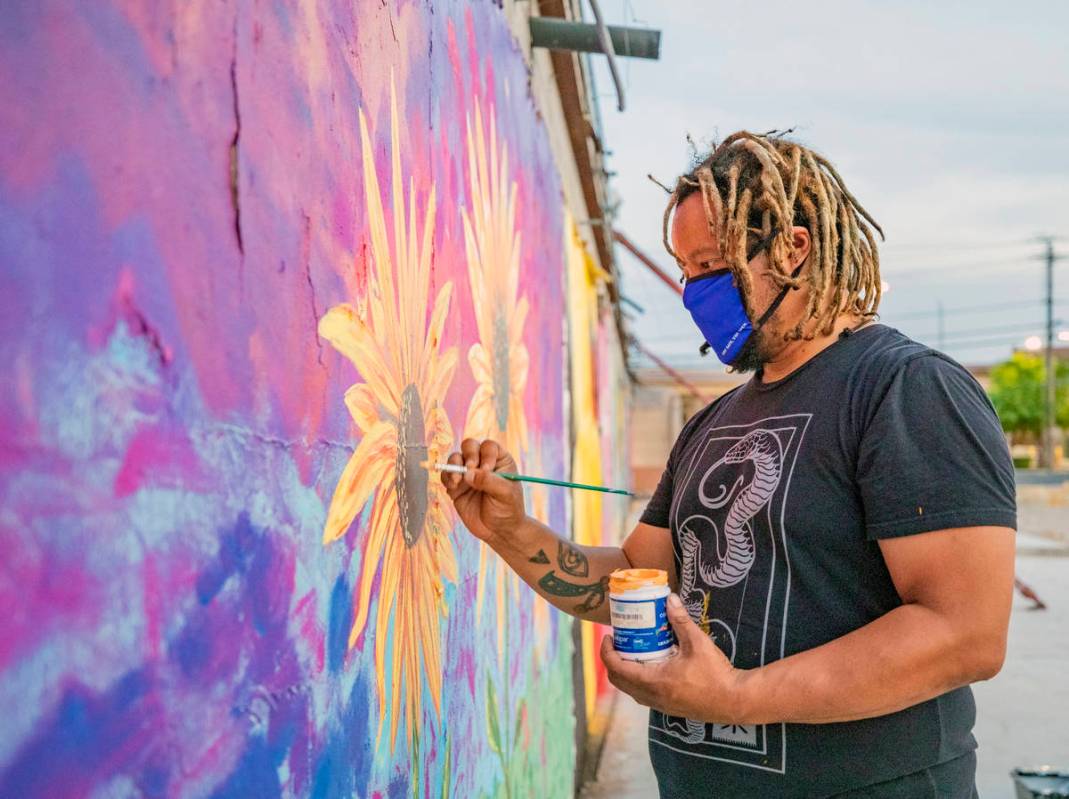 Multidisciplinary artist and community activist Brent Holmes works on a mural located on the Mo ...