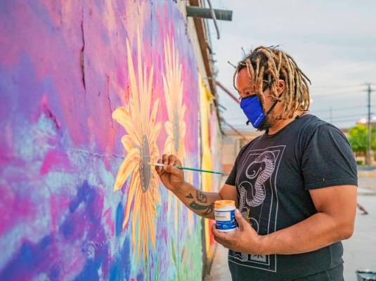 Multidisciplinary artist and community activist Brent Holmes works on a mural located on the Mo ...