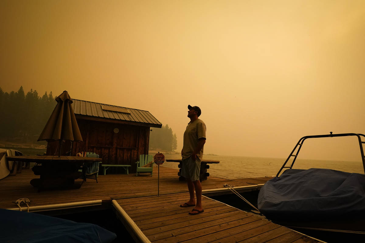 A business owner, who declined to give his name, looks up at the smoke-covered sky from the Cre ...