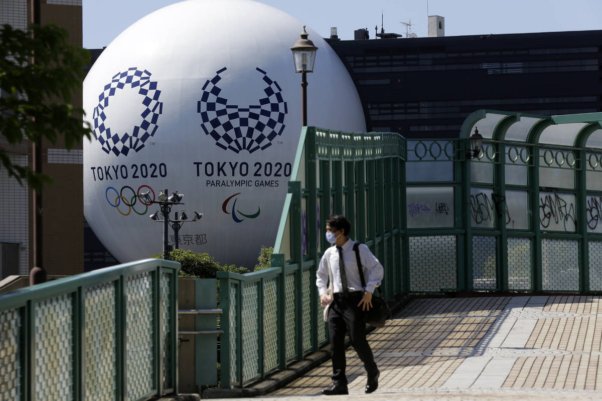 A man wearing a mask walks on a pedestrian bridge over the train tracks Wednesday, Sept. 9, 202 ...