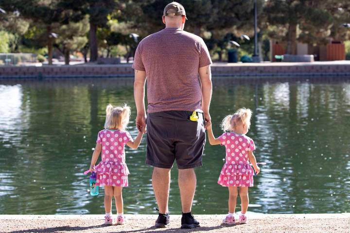 Derrick Agnew relaxes with his daughters Penelope, 3 , left, and Eloise, 2, at Sunset Park on T ...