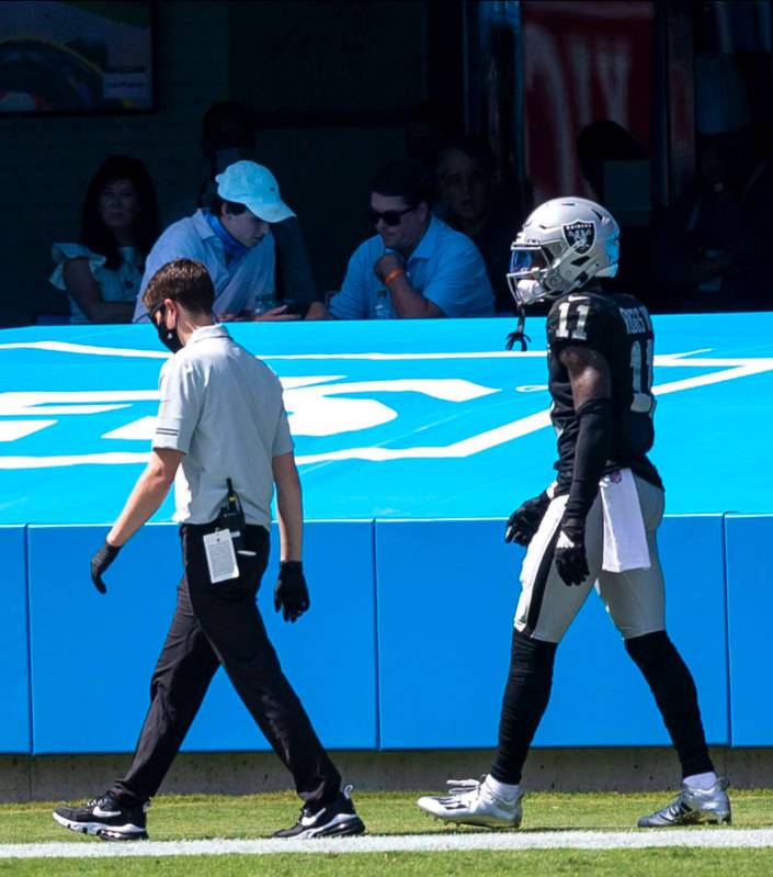 Las Vegas Raiders wide receiver Henry Ruggs III (11) walks off the field with a trainer in the ...