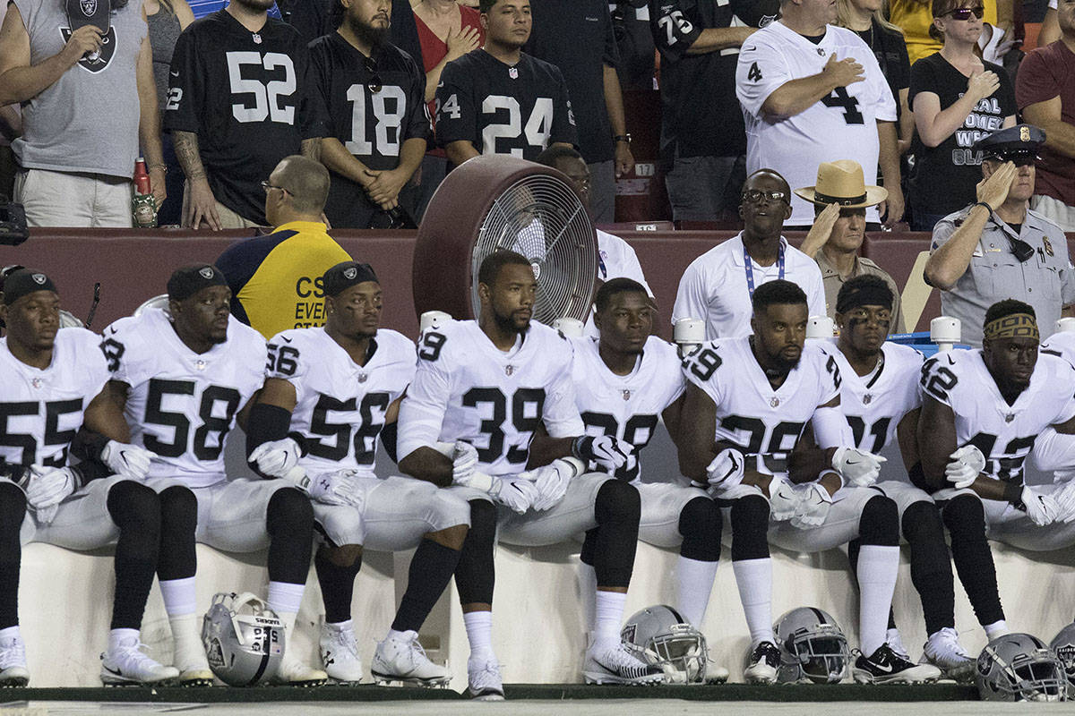 Some of the Oakland Raiders interlock arms and sit during the national anthem before their game ...