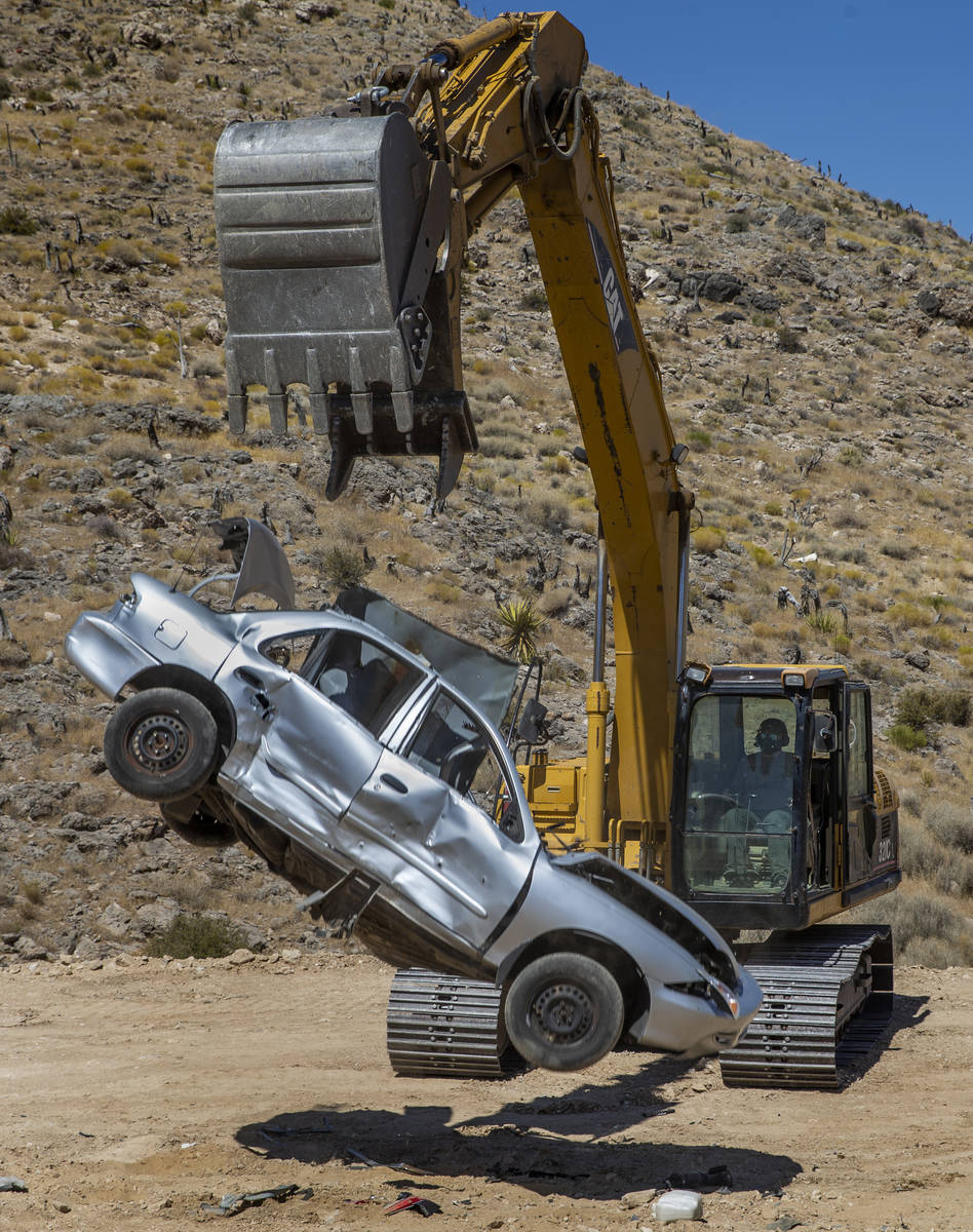 Christopher Lawrence releases a car from the bucket of a Caterpillar Excavator, one of the extr ...