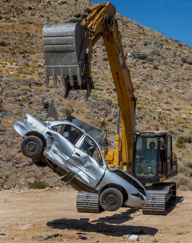 Christopher Lawrence releases a car from the bucket of a Caterpillar Excavator, one of the extr ...