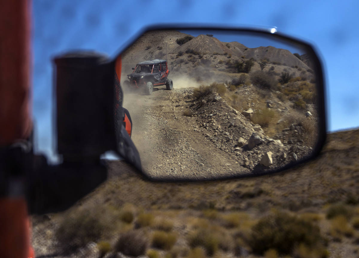 A Honda Talon is reflected in the mirror of another as the vehicles move along the miles of dir ...