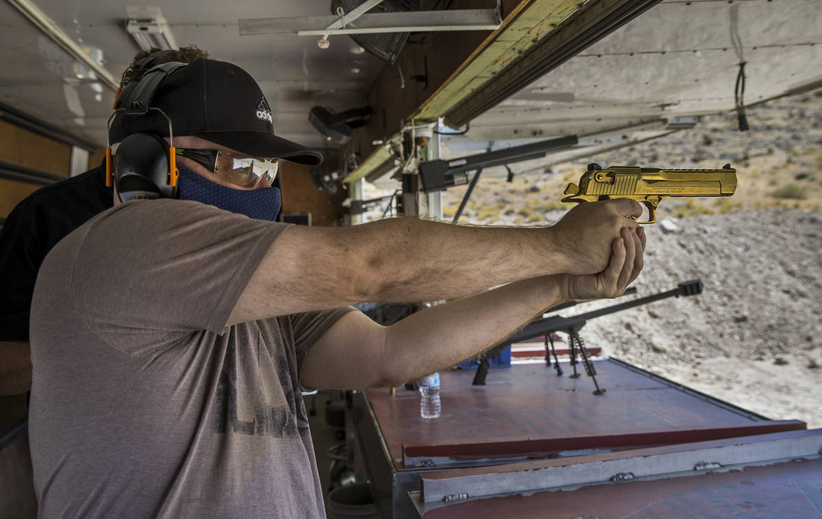 Christopher Lawrence aims a titanium gold Desert Eagle pistol on the Adrenaline Mountain gun ra ...
