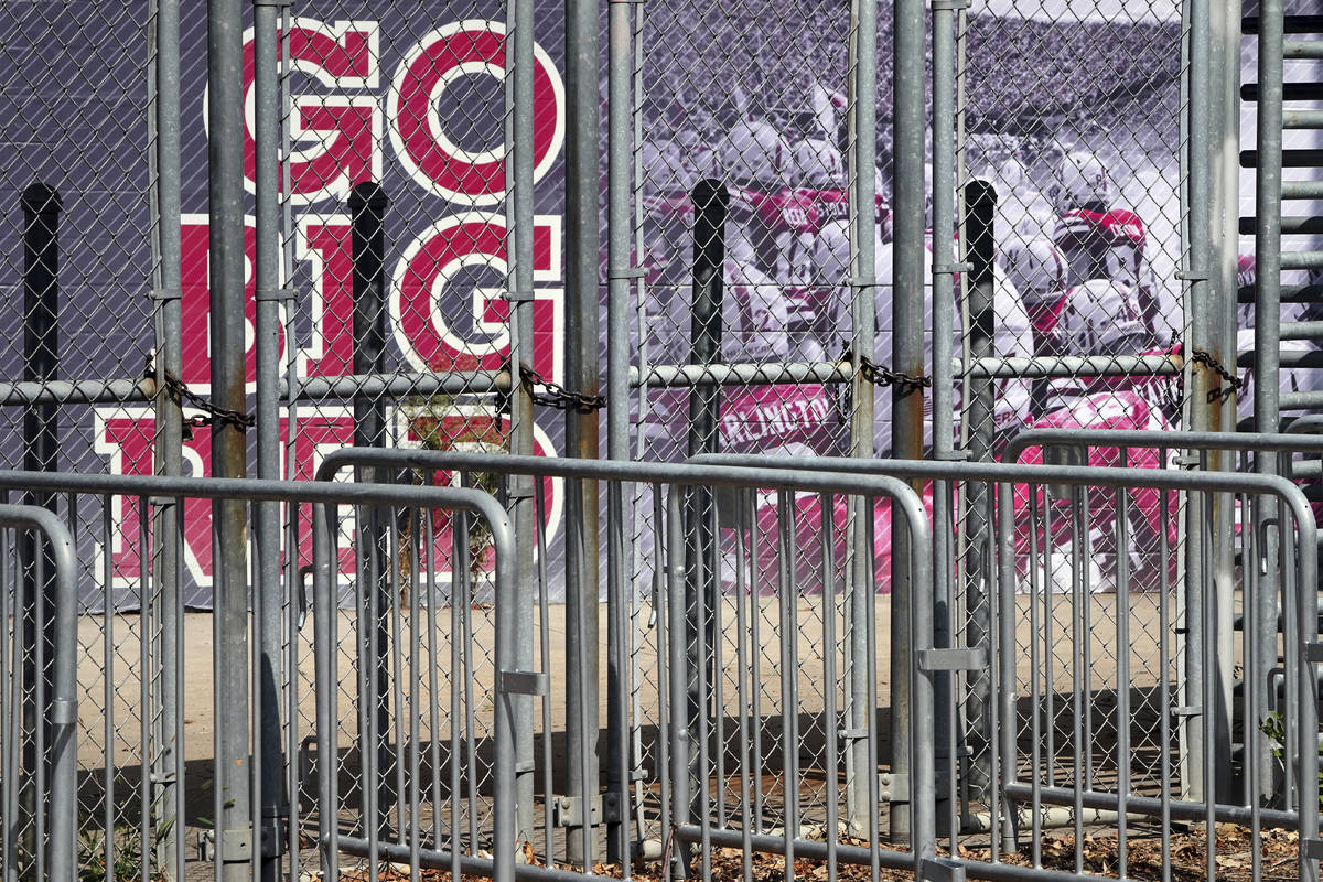 A mural showing Nebraska football players and Go Big Red lettering are seen past locked gates a ...