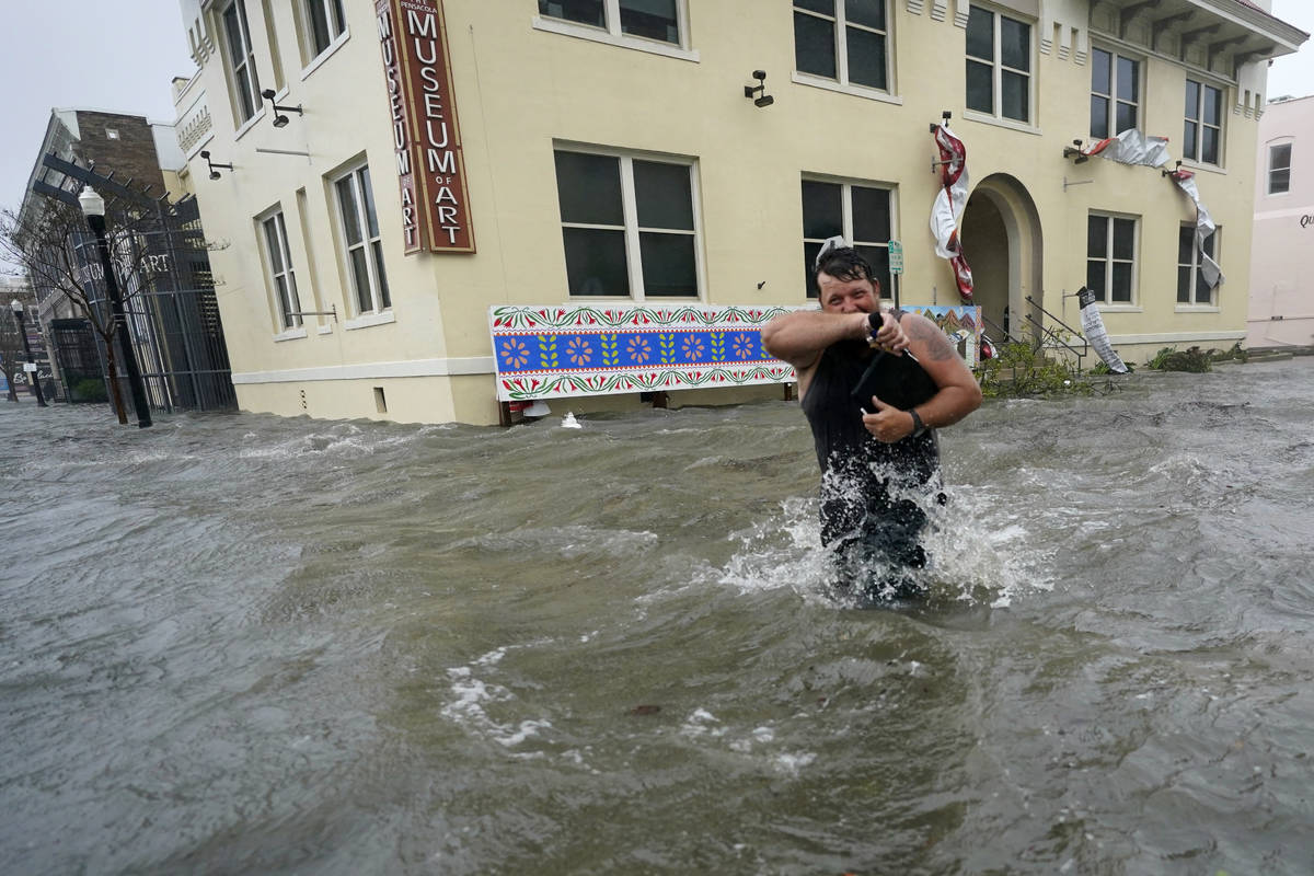 Trent Airhart wades through flood waters, Wednesday, Sept. 16, 2020, in downtown Pensacola, Fla ...