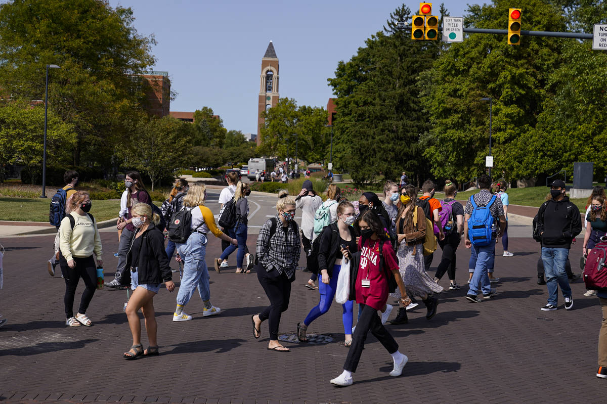 Masked students cross an intersection on the campus of Ball State University in Muncie, Ind., T ...