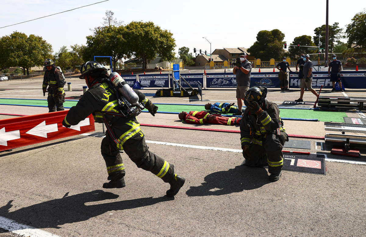 North Las Vegas firefighter Jason Coates, left, runs with the baton after being handed it from ...