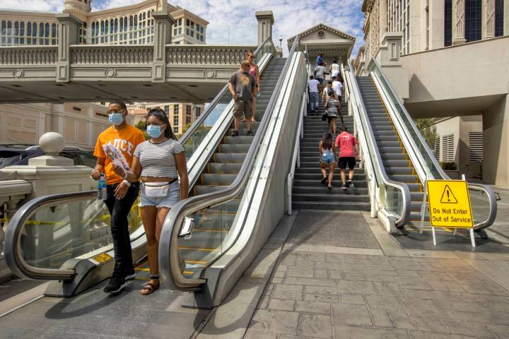 Pedestrians work their way down and up the bridge that crosses East Flamingo Road between Caesa ...