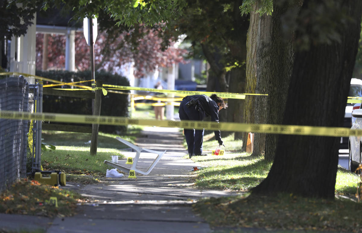 A Rochester police technician picks up some items as evidence near the home where a fatal house ...