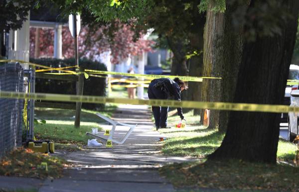 A Rochester police technician picks up some items as evidence near the home where a fatal house ...