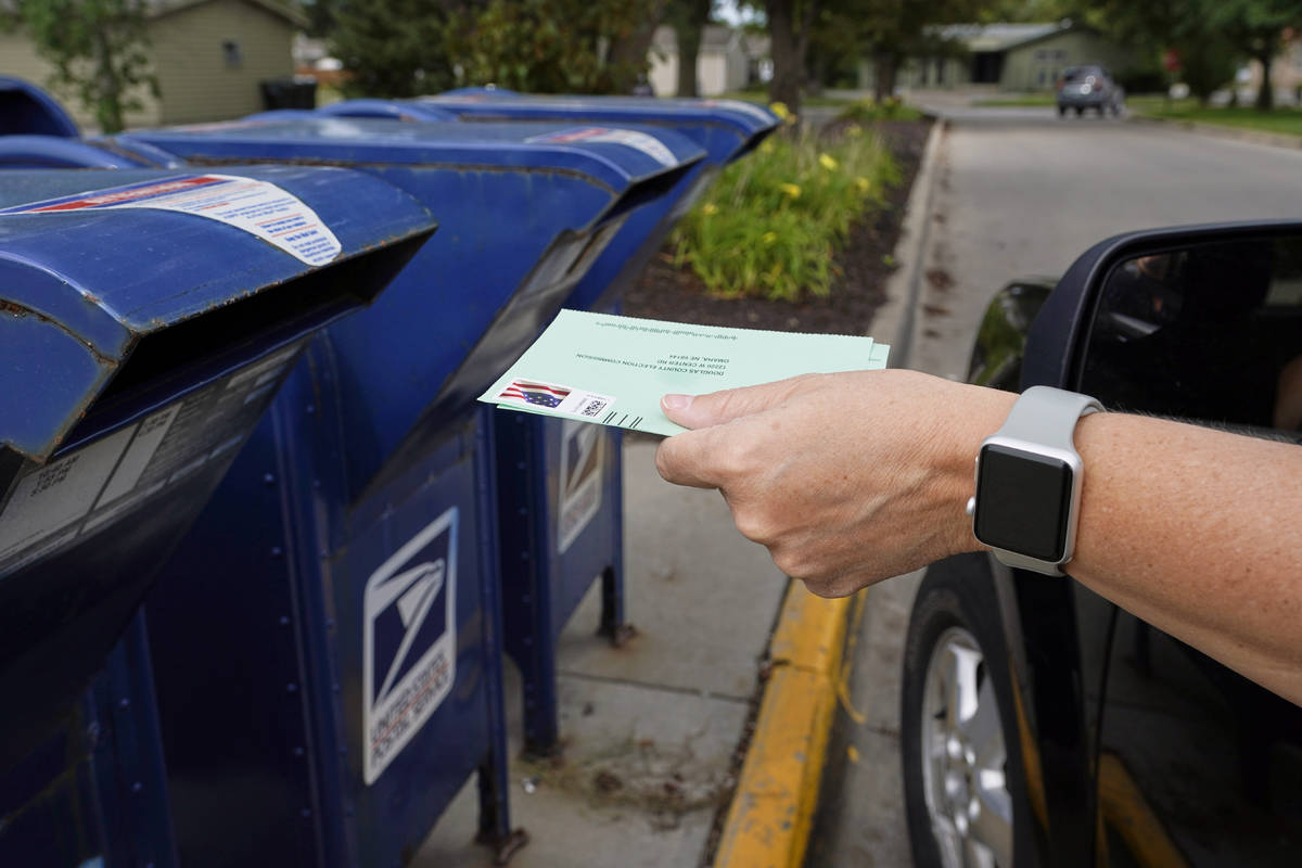 A person drops applications for mail-in ballots into a mailbox in Omaha, Neb., Aug. 18, 2020. ...