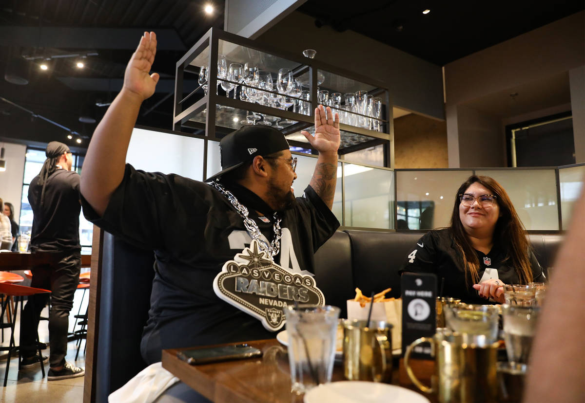 Mike Aguiniga, left, makes a gesture applauding the Raiders first touchdown next to his wife, M ...