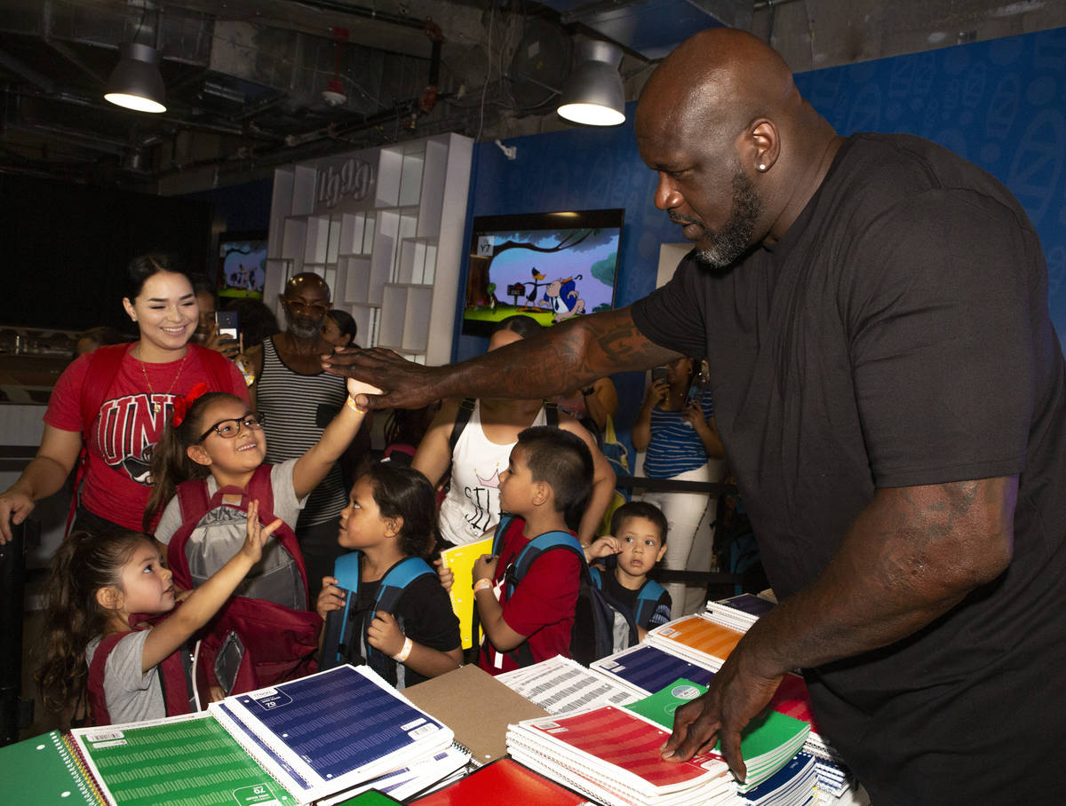 Isabella Hidalgo, 7, center, gives a high-five to former NBA star Shaquille O'Neal, while her s ...