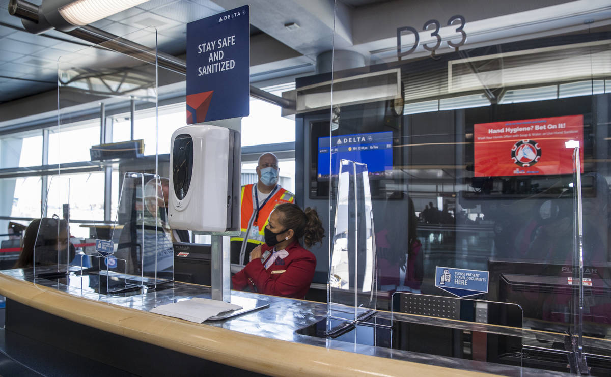 Delta Airlines personnel sit behind plexiglass and have hand sanitizer available at the gates t ...