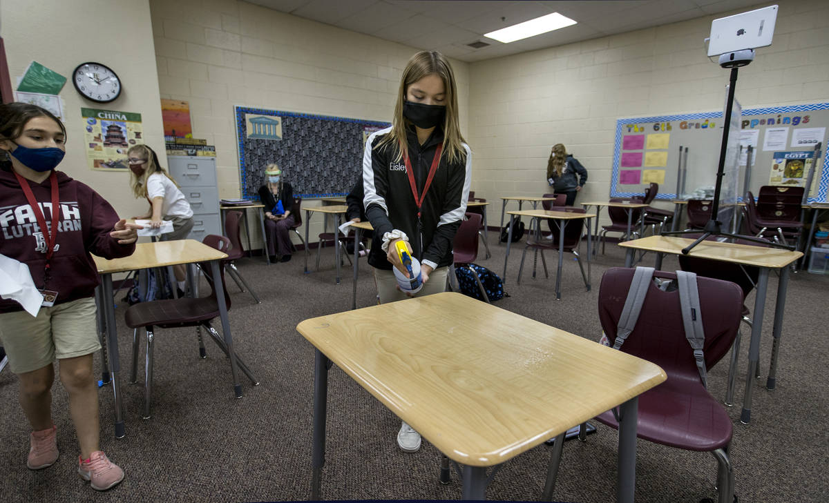 Student Eisley Wheat, 12, center, sprays down a desk for Alyssa Kazemi, 11, as they are cleaned ...