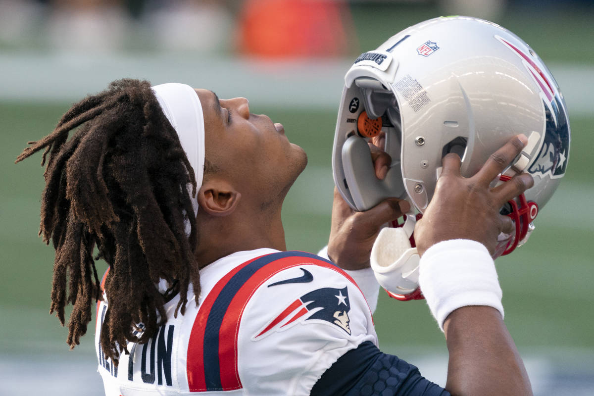 New England Patriots quarterback Cam Newton puts on his helmet before an NFL football game agai ...