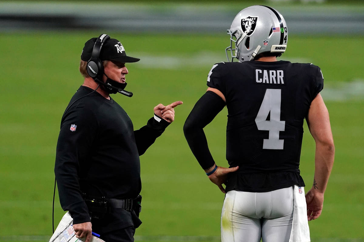 Las Vegas Raiders head coach Jon Gruden, left, speaks with quarterback Derek Carr (4) during th ...