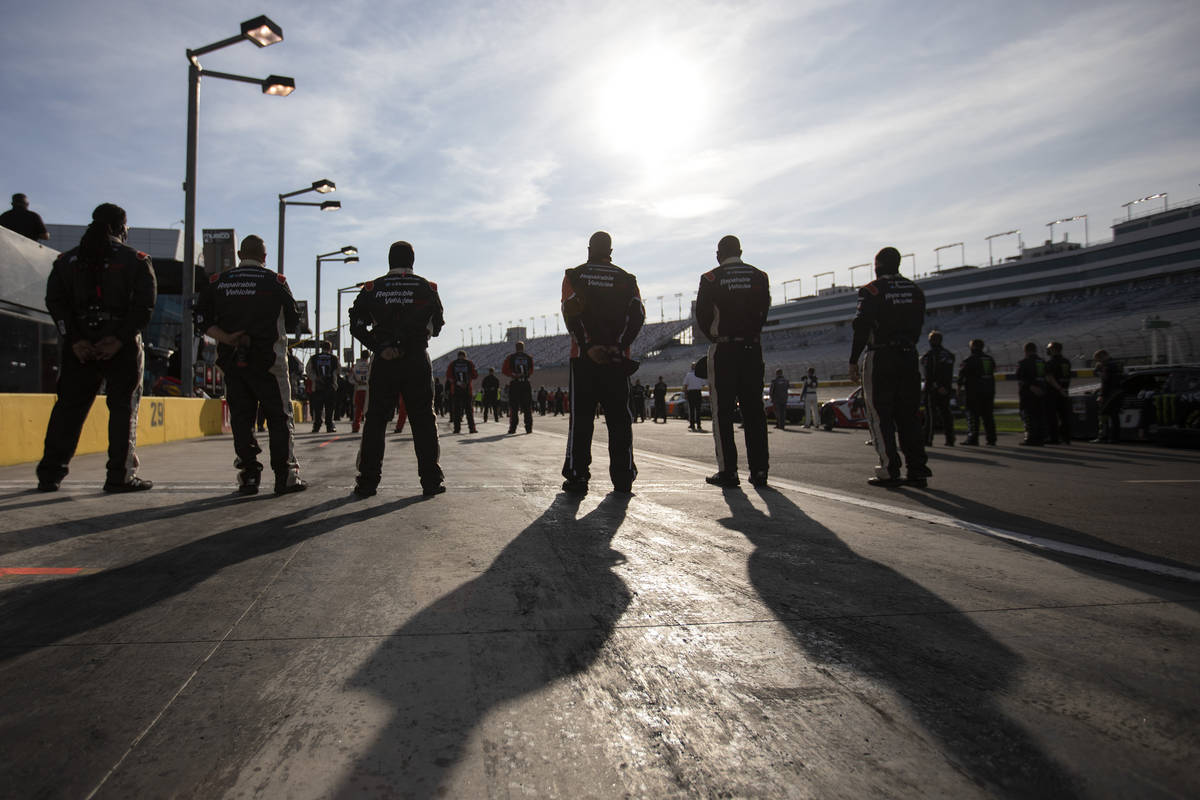 Race participants stand socially distanced as the national anthem plays before the NASCAR Xfini ...